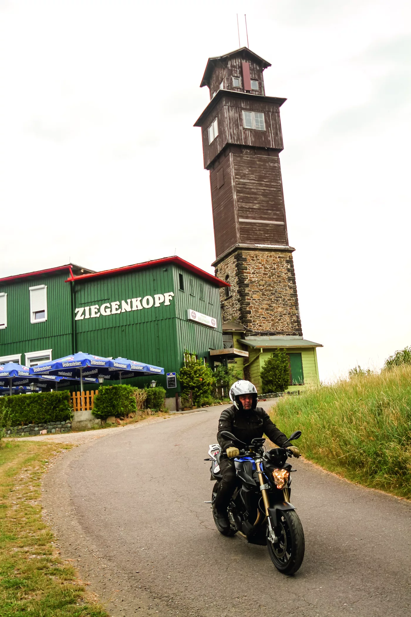 Motorrad auf dem Weg zum hölzernen Ziegenkopfturm mit Berggasthof